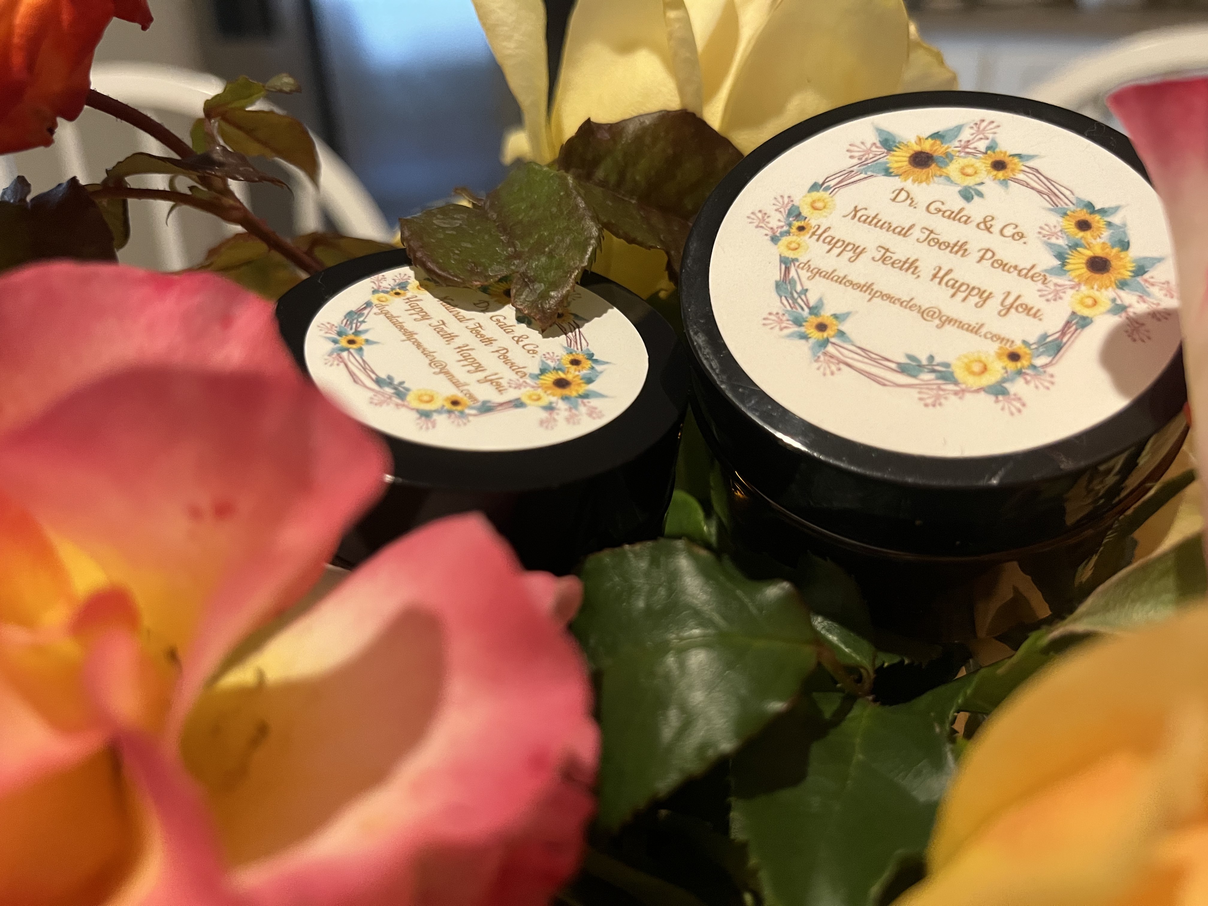 Powder Dent Natural Tooth Powder jars surrounded by roses